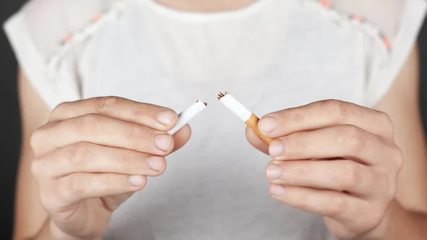 Koncepce zdraví, zákaz kouření, zlozvyk. dívka drží rozbitou cigaretu v rukou zblízka — Stock fotografie