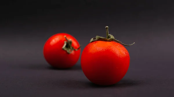 Red fresh juicy cherry tomatoes on a black background close-up, vegetable — Stock Photo, Image