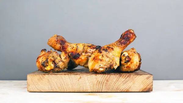 Grillade kycklingben på en träplatta på en grå bakgrund. saftig krispig kyckling, rejäl lunch tillagad utomhus, B-B-Q — Stockfoto