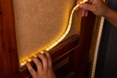 installation of LED strip with warm yellow light on the door for decorative lighting clipart