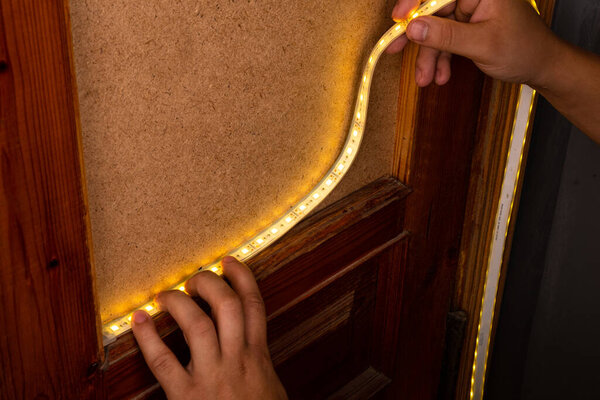 installation of LED strip with warm yellow light on the door for decorative lighting