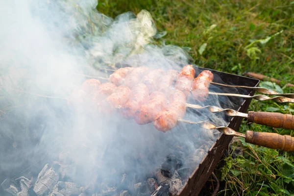 Saucisses de porc grillées dans la fumée, nourriture de pique-nique d'été cuite à l'extérieur — Photo