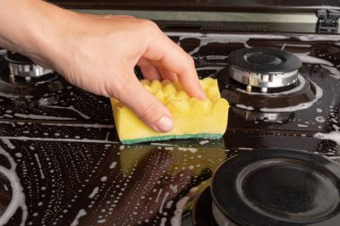 Mutfaktaki gaz sobasını yıkıyorum. 