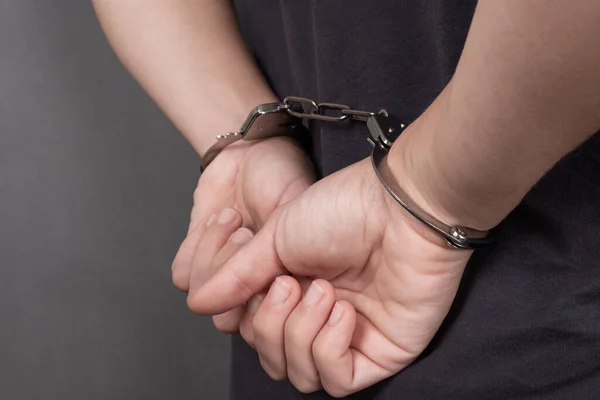 Verhafteter in Handschellen auf dunklem Hintergrund in Großaufnahme, gefesselte Hände auf dem Rücken — Stockfoto