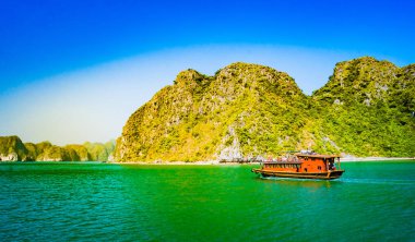 Halong Körfezi Vietnam 'da gün batımında ön planda tur botlarıyla.