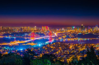 Istanbul Boğaziçi Köprüsü güzel aydınlatmalı gün batımında. Çamlıca Tepesi'nden gece görünümü. Istanbul, Türkiye.