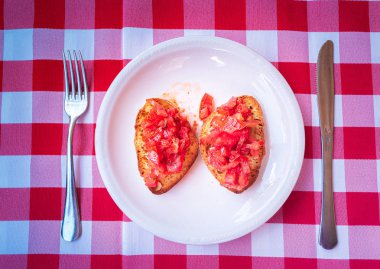 Bruschetta Kırmızı ve Beyaz Damalı Masa Runner bıçak ve çatal ile bir tabak üzerinde görev yaptı.