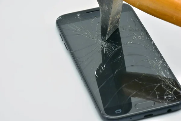 Broken mobile phone screen with a hammer