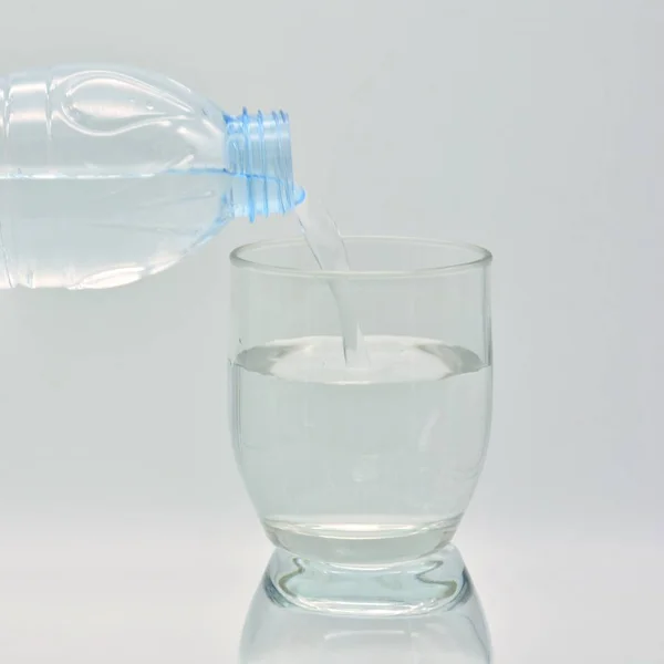 Butelka Wody Napełniająca Szklany Kubek — Zdjęcie stockowe