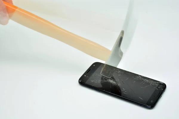 Hammer breaking the screen of a mobile phone in motion