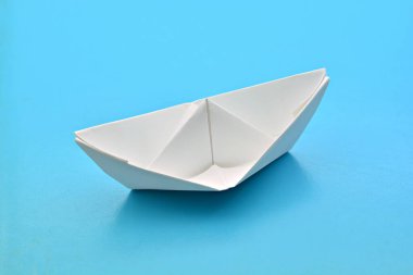 Mavi arka planda beyaz kağıt tekne