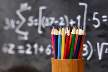 Yazılı bir tahtanın arka planına sahip renkli kalemler