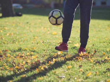 Parkta futbol ile güneşli bir sonbahar gününde pratik futbolcu