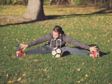 Parkta futbol ile güneşli bir sonbahar gününde germe futbolcu