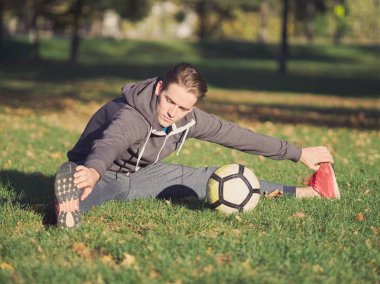 Parkta futbol ile güneşli bir sonbahar gününde germe futbolcu