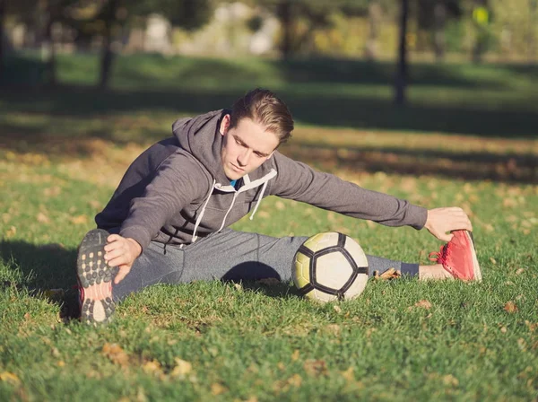 Parkta futbol ile güneşli bir sonbahar gününde germe futbolcu