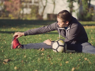 Parkta futbol ile güneşli bir sonbahar gününde germe futbolcu