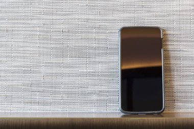 Çevrimiçi bağlantısı, kablosuz Internet teknolojisi. E-ticaret iş. Boş ekran ile beyaz ve gri duvar ahşap masa üstünde hareket eden telefon. Resim için kısa mesaj ekleyin. Tasarım sanat çalışmaları için fon.