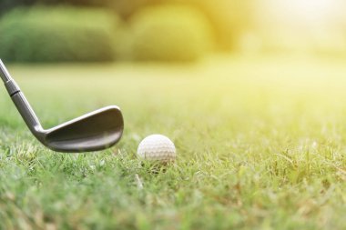 Golf topu ile güneş ışığı ile yeşil çimenler üzerinde golf club.