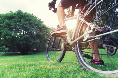 Park kavramında Bisiklete binme. Yeşil alan Park günbatımı üzerinde bisiklet closeup. Resim için kısa mesaj ekleyin. Tasarım sanat çalışmaları için fon.