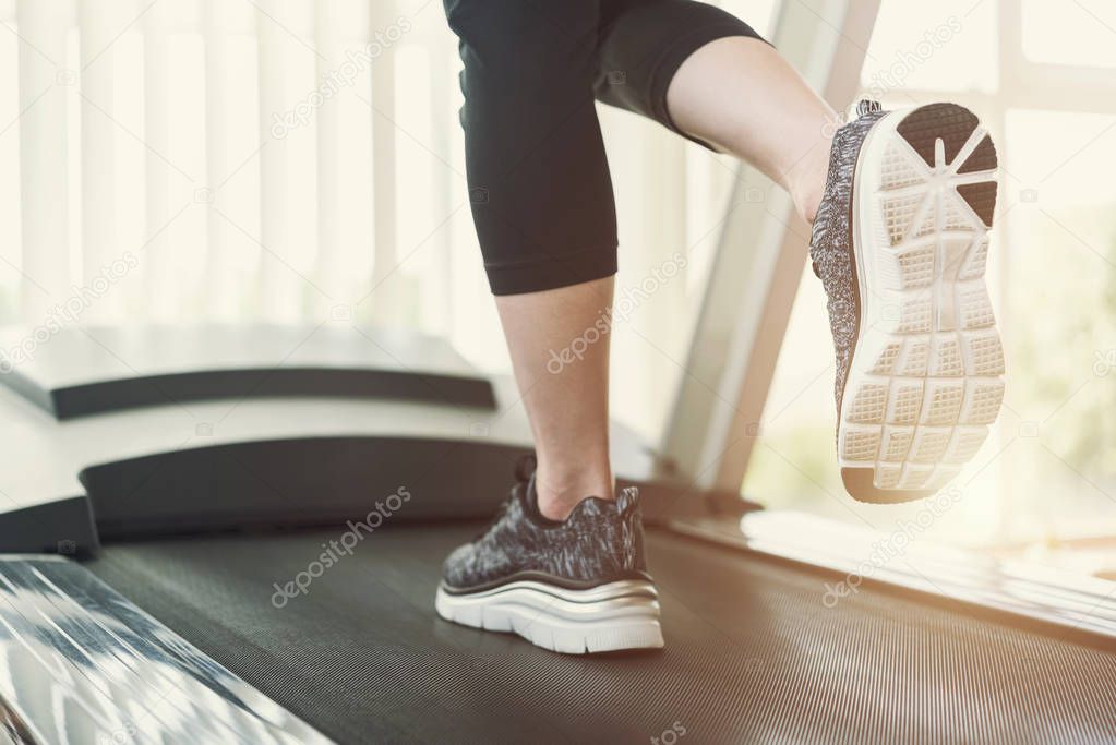 Healthy and fitness concept. Sport people running on treadmill at gym in the morning with sunlight. Close up of shoes shot with free copy space background.