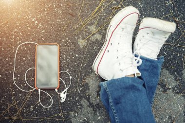 Teknoloji ve yaşam tarzı kavramı. Closeup Ayakkabı ve katta kulaklık ile hareket eden. Kez Bahçe dinleme müzik ile rahatla.