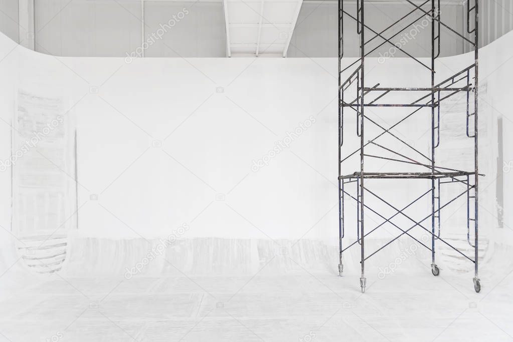 Construction and abstract background. White room renovating work process with white painted on wall and floor with scaffolding. Picture for add text message. Backdrop for design art work.