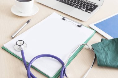 Boş tıbbi Pano ve ahşap masa, işyeri bir doktor arka plan üzerinde stetoskop.