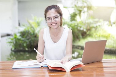 Cute asian student reading, doing report and home work in university. clipart