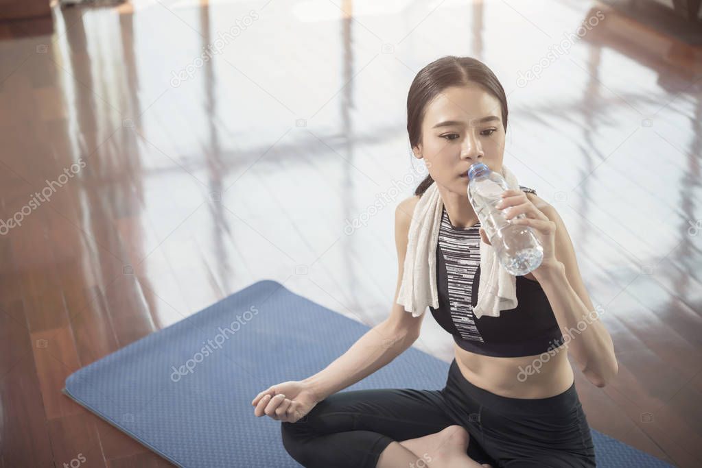 Healthy and fitness concept. Beautiful sport woman take a rest with drinking after workout at gym.
