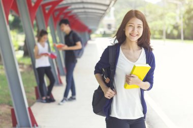 Genç öğrenci mutlu gülümseyen okula yürüme. Eğitim ve okul kavramı geri.