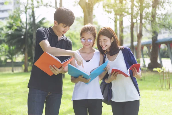 Students holding books and talking while standing in park. Education in school or university. Back to school concept.