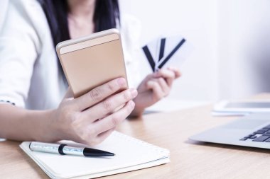 Ofiste masada mobil ve kredi kartı tutan closeup el.
