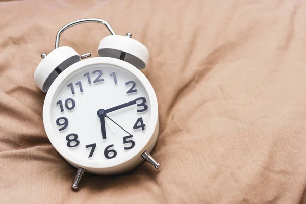 Concepto de fondo temporal. Reloj despertador en la cama, despertador por la mañana —  Fotos de Stock