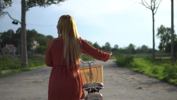 公園を歩いて自転車を持つ若い女性 — ストック動画