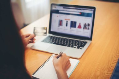 Young people holding credit card and using laptop computer choose some products. Online shopping concept.