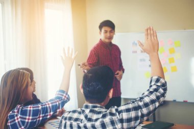 Group of young people business sitting on conference together while people raising hand ask questions.