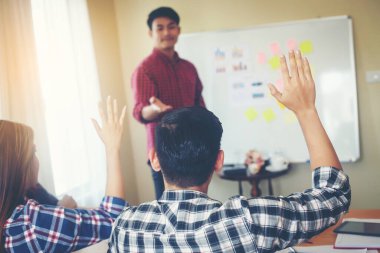 Group of young people business sitting on conference together while people raising hand ask questions.