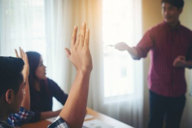 Group of young people business sitting on conference together while people raising hand ask questions.