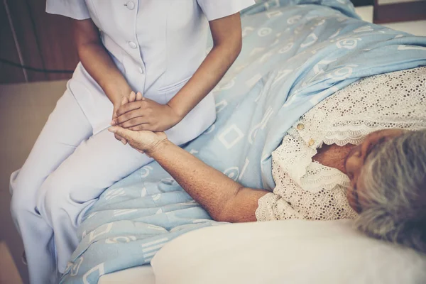 若い看護師の終わりは彼女を保持高齢患者の世話をし 彼女は入院中に快適に感じさせる — ストック写真