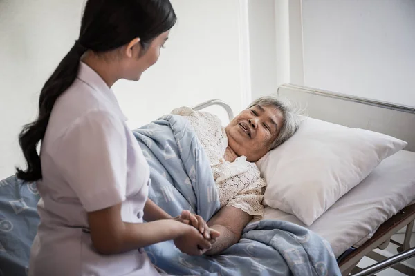 若い看護師の終わりは彼女を保持高齢患者の世話をし 彼女は入院中に快適に感じさせる — ストック写真
