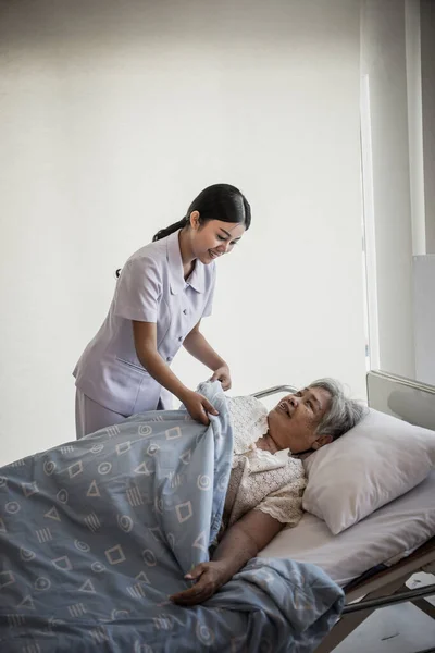 入院中の高齢者の世話をする若い看護師 — ストック写真