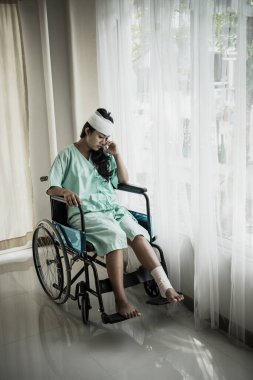 Hastanenin odasındaki tekerlekli sandalyede oturan kadın hastaların kafasında ağrı var..
