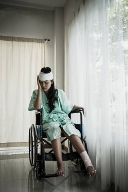 Hastanenin odasındaki tekerlekli sandalyede oturan kadın hastaların kafasında ağrı var..