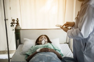 Hastanedeki hastaya bakarken doktor panoya yazı yazıyor..