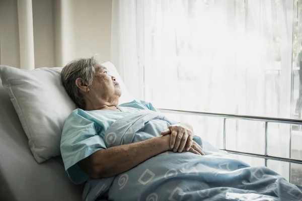 ベッドに座っている高齢者は孤独を持って訪れる親戚を待っている — ストック写真
