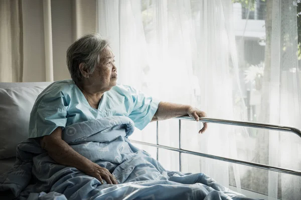 ベッドに座っている高齢者は孤独を持って訪れる親戚を待っている — ストック写真