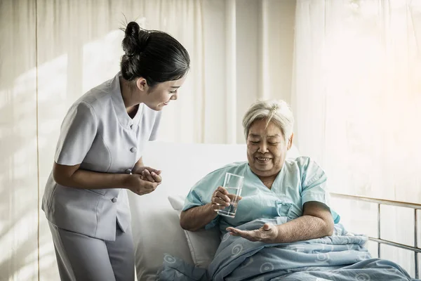 シニア女性の医療薬を与える看護師 — ストック写真