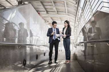 İş arkadaşları birlikte ofise yürürken tabletteki işlere bakarlar..