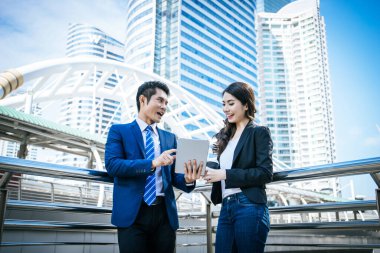 İş arkadaşları birlikte ofise yürürken tabletteki işlere bakarlar..